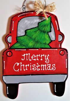 a red truck with a christmas tree painted on the front and back side, hanging from a rope