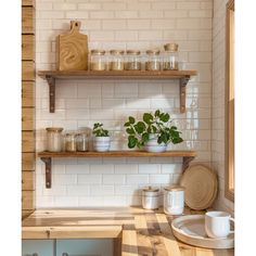 a kitchen with wooden shelves and white tiles on the wall, potted plants in front of them