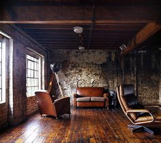 an empty room with two leather chairs and one recliner