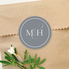 the monogrammed wedding stickers are on top of a brown paper bag with white flowers