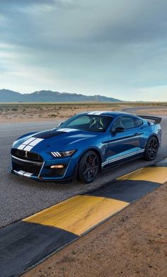 a blue sports car driving on the road in the middle of an open desert area