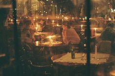 people sitting at tables in a restaurant with lit candles