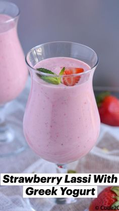 two glasses filled with strawberry milkshakes on top of a white cloth next to strawberries