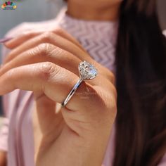 a woman wearing a diamond ring on her finger and holding it up to the camera