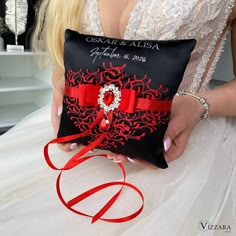 a woman holding a black and red pillow with a red ribbon around it's edge