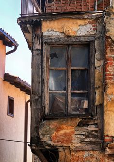 an old brick building with a broken window and balconies on the top floor