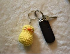 a crocheted yellow bird keychain sitting on top of a white rug