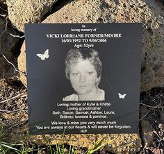 a plaque with a picture of a woman on it in front of some rocks and grass