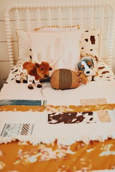 two stuffed animals laying on top of a bed next to pillows and blankets in a room