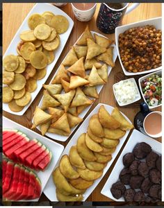 a table topped with plates of food and bowls of dips on top of it