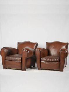 two brown leather chairs sitting next to each other