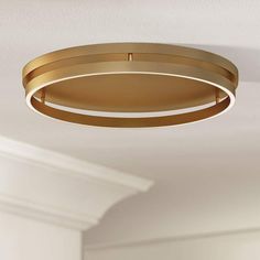 a gold circular light fixture hangs from the ceiling in a room with white walls and ceilings