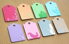 six tags with different designs on them sitting on top of a wooden table next to each other