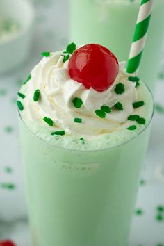 two green drinks with whipped cream and a cherry on top