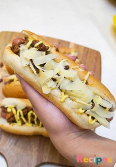 two hot dogs with toppings are being held by someone