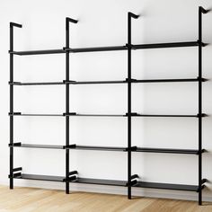 an empty white room with black shelving and wood flooring on the wall, in front of a plain white wall