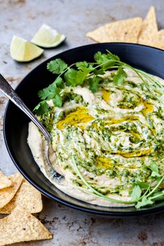 a black bowl filled with guacamole and tortilla chips