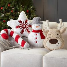 two snowmen and a reindeer sitting on a couch with christmas decorations in the background