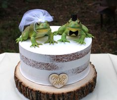 two frogs are sitting on top of a cake