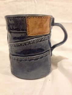 a close up of a coffee cup on a white surface with a brown leather handle