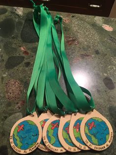 four wooden tags with green ribbons on top of a marble countertop next to a clock