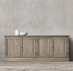 a white vase sitting on top of a wooden cabinet next to a bowl and cup