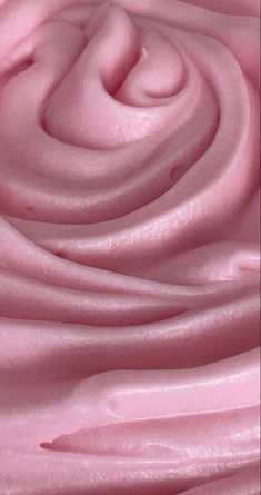 a close up view of pink icing with swirls in the center and on top