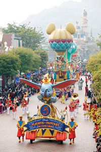 a parade float in the middle of a street with people on it and balloons flying above