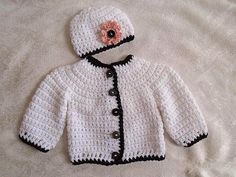 a crocheted white jacket with a flower on the collar and black trims