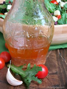 a glass pitcher filled with liquid sitting on top of a wooden table next to vegetables