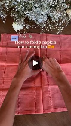 someone is making a napkin out of red material with white flowers in the background and text that reads, how to fold a napkin into a pumpkin