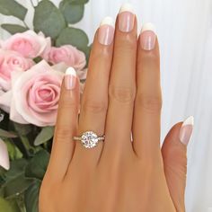 a woman's hand with a ring on it and a rose in the background