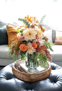 a vase filled with flowers sitting on top of a blue ottoman