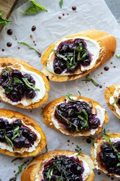 small crostini with blueberries and cream cheese on top, sitting on parchment paper