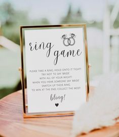 a sign that says ring game sitting on top of a wooden table next to a white feather