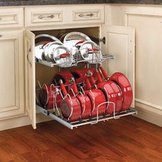 an open cabinet with many red pots and pans in the bottom rack on it