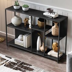 a black shelf with vases and books on it next to a rug in a living room