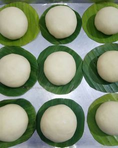 eight uncooked doughnuts sitting on top of a green leafy tray