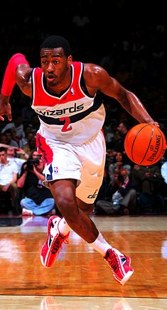 a basketball player dribbles the ball during a game with fans in the stands