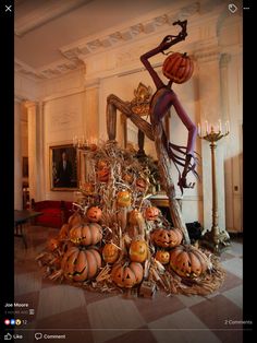 a pile of pumpkins sitting on top of a floor next to a man statue