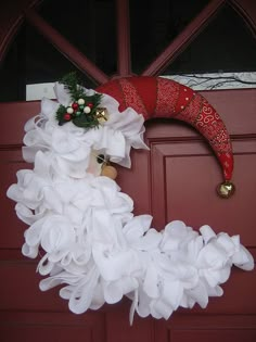 a red door with a wreath on it and white ruffles hanging from the front