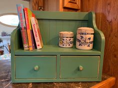 a green shelf with books and jars on it