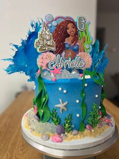 a birthday cake with an image of ariel the mermaid on top and under the seaweed