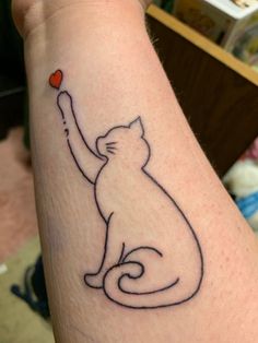 a cat with a red heart in its hand tattoo on the left arm and wrist