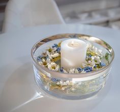 a white candle sitting in a glass bowl filled with flowers