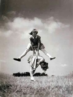 an old black and white photo of a woman doing a handstand in the grass