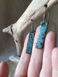 a pair of earrings that have been made to look like rectangles with rust on them