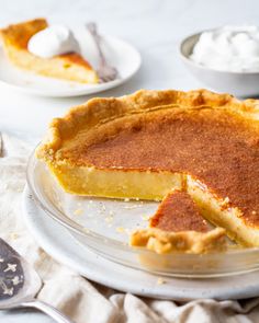 a piece of pie on a plate with whipped cream and spoons next to it