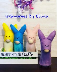 three small stuffed animals sitting on top of a wooden table next to a sign that says gnomes by oliva