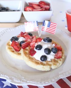 two waffles with strawberries and blueberries are on a patriotic table cloth